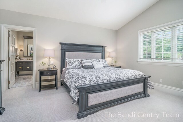 18635 N Fruitport Rd, Spring Lake, MI 49456 - bedroom with light colored carpet, vaulted ceiling, baseboards, and ensuite bath