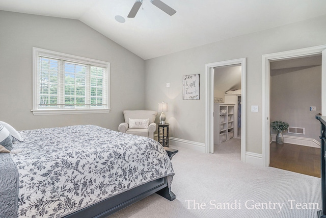 carpeted bedroom with a walk in closet, ceiling fan, and lofted ceiling