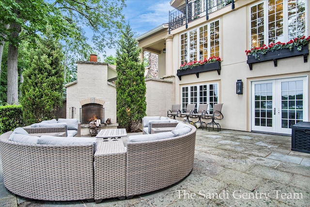 view of patio featuring an outdoor living space with a fireplace, french doors, and a balcony