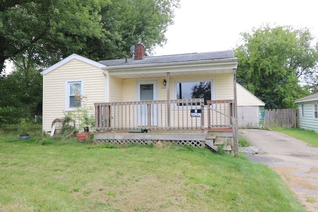 ranch-style home featuring covered porch and a front yard