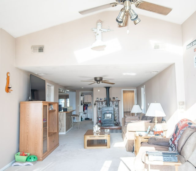 carpeted living room with a wood stove and vaulted ceiling