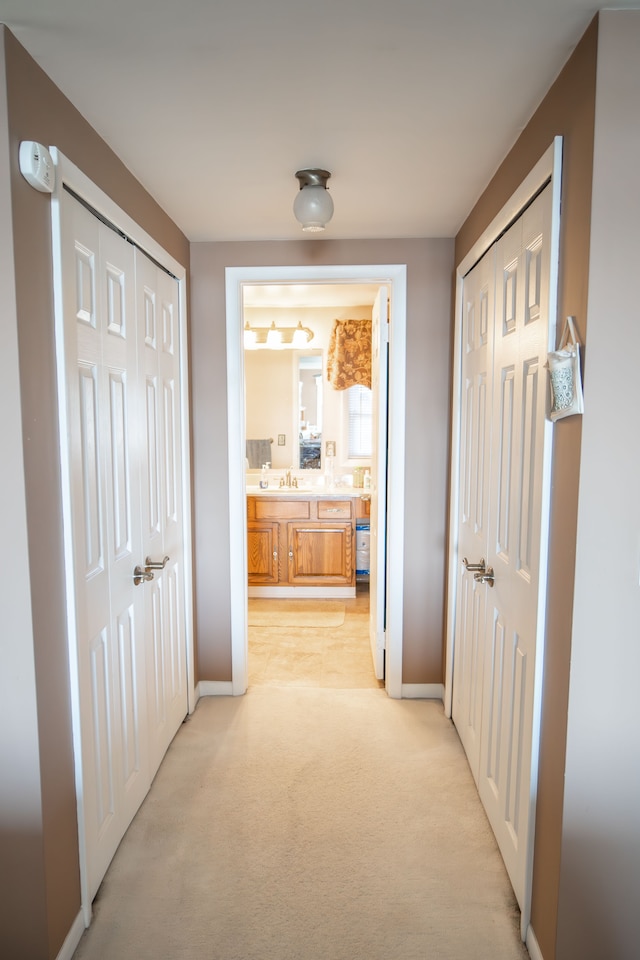 hallway featuring light colored carpet