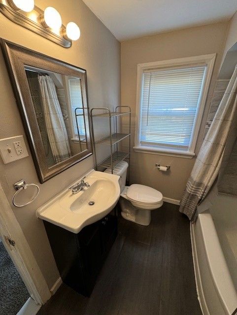 full bathroom featuring hardwood / wood-style flooring, vanity, toilet, and shower / tub combo