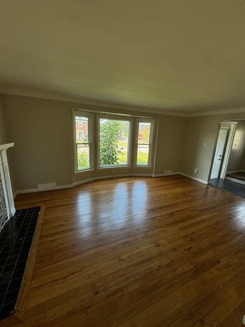 unfurnished living room featuring a fireplace, dark hardwood / wood-style floors, and ornamental molding