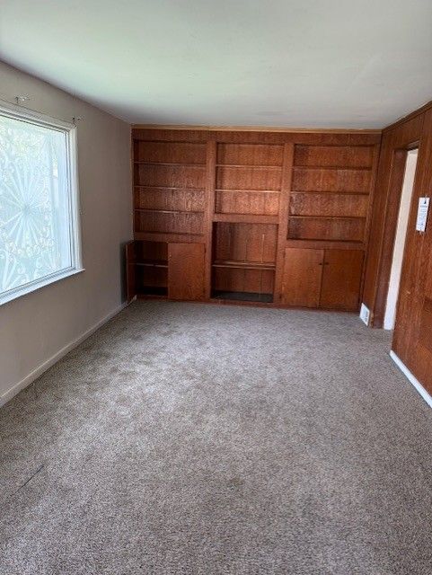 unfurnished living room featuring built in features and light colored carpet