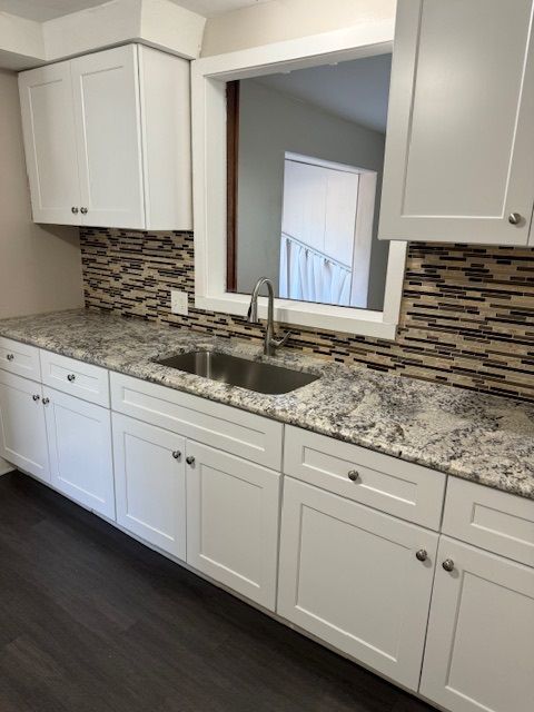 kitchen featuring tasteful backsplash, sink, white cabinets, and dark wood-type flooring