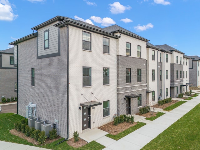 exterior space featuring central air condition unit and a front lawn