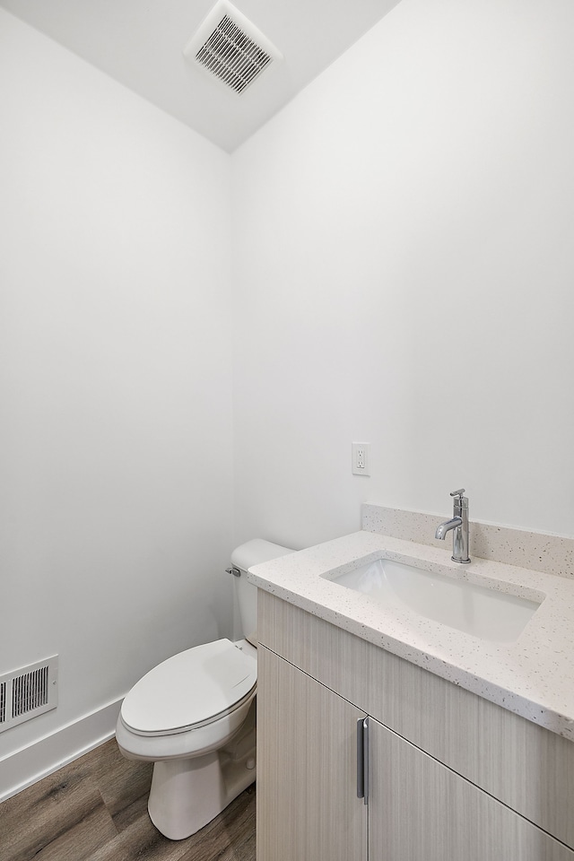 bathroom with hardwood / wood-style floors, vanity, and toilet