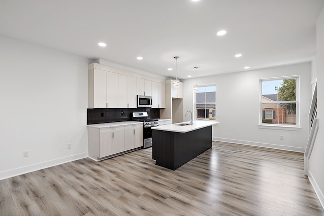 kitchen with a center island with sink, white cabinets, stainless steel appliances, and sink