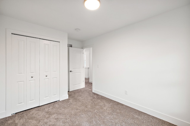 unfurnished bedroom with light colored carpet and a closet