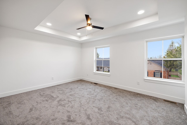 empty room featuring carpet flooring, ceiling fan, and a tray ceiling