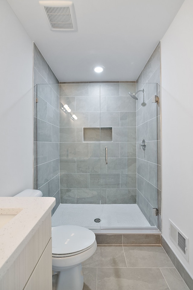 bathroom featuring tile patterned floors, vanity, toilet, and a shower with shower door