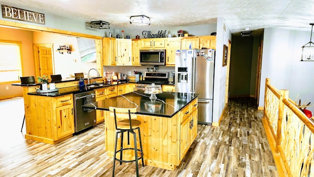 491 Bitter Creek Ln, Pierson, MI 49339 - kitchen featuring stainless steel appliances, a sink, a peninsula, light wood-style floors, and dark countertops