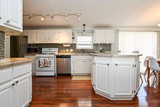 kitchen featuring white cabinets, decorative backsplash, dark hardwood / wood-style flooring, and stainless steel appliances