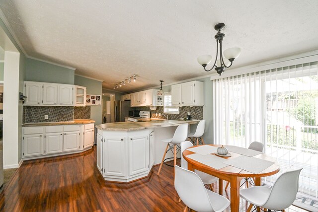 dining space with dark hardwood / wood-style flooring, track lighting, a textured ceiling, crown molding, and a chandelier