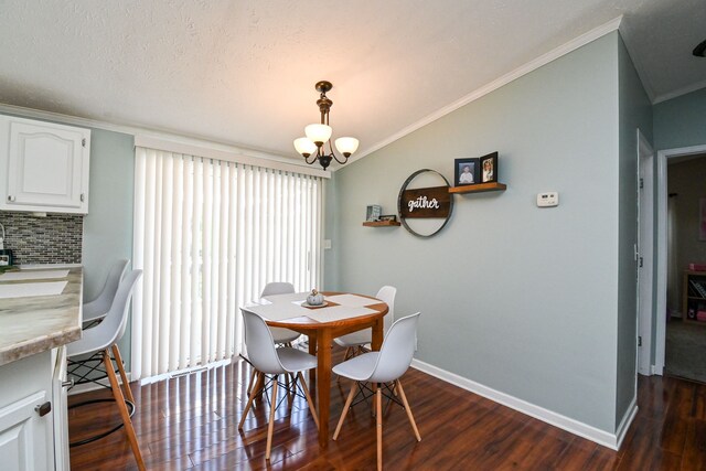 dining space with a textured ceiling, dark hardwood / wood-style flooring, an inviting chandelier, and ornamental molding