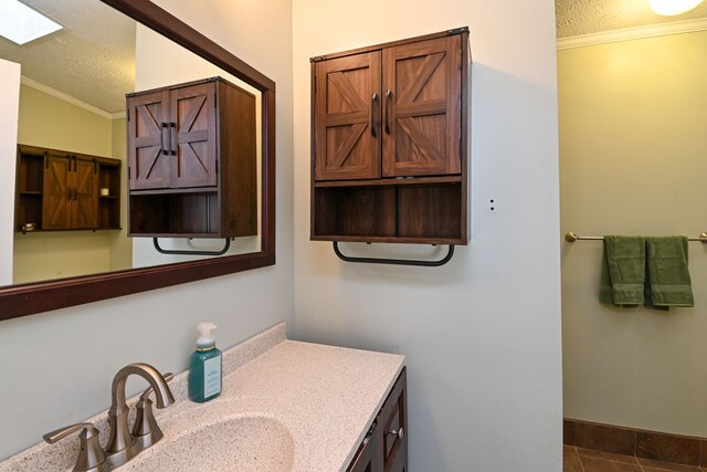 bathroom with a textured ceiling, vanity, vaulted ceiling, crown molding, and tile patterned flooring