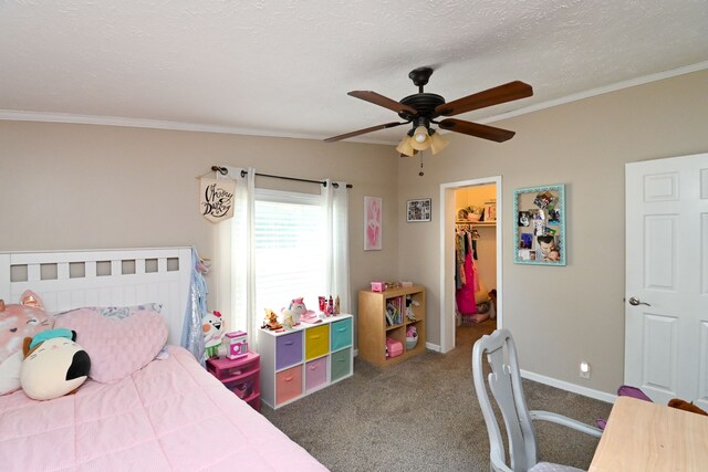 bedroom with a walk in closet, ornamental molding, ceiling fan, dark colored carpet, and a closet