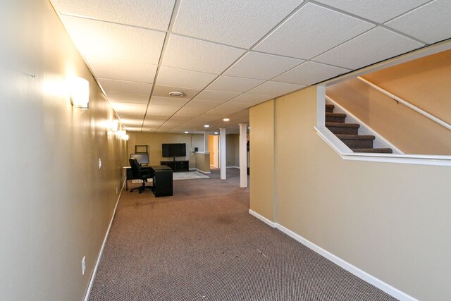 corridor featuring carpet flooring and a paneled ceiling