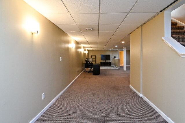 hall with carpet flooring and a paneled ceiling