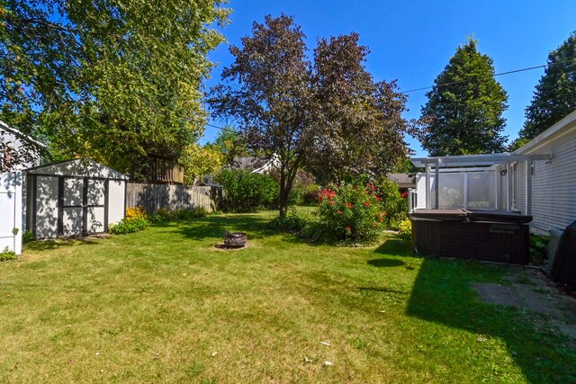 view of yard featuring a storage shed, an outdoor fire pit, and a hot tub