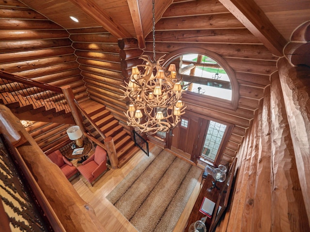 stairs with hardwood / wood-style flooring, an inviting chandelier, rustic walls, and wood ceiling