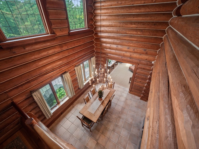 unfurnished living room featuring tile patterned floors, a notable chandelier, and rustic walls