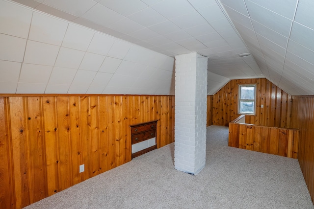 bonus room with carpet flooring, lofted ceiling, and wood walls