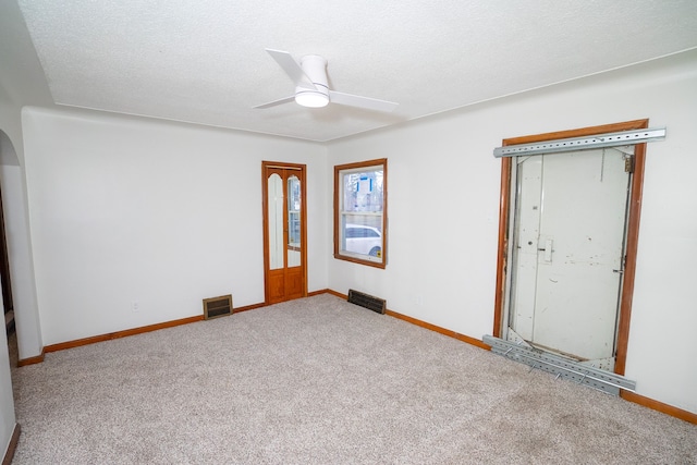 carpeted spare room with a textured ceiling and ceiling fan