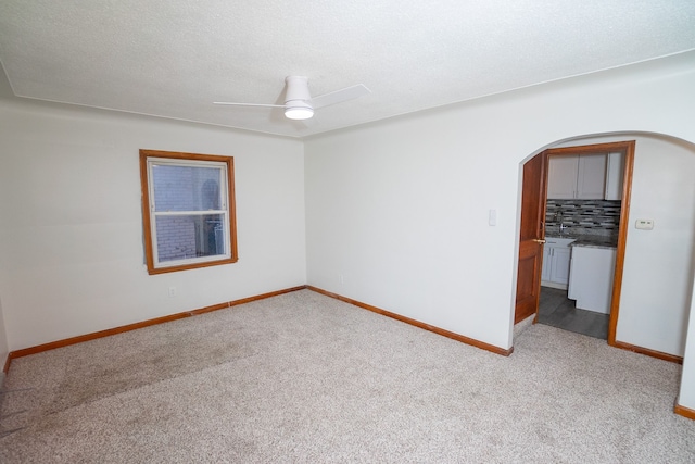 carpeted spare room featuring ceiling fan and a textured ceiling