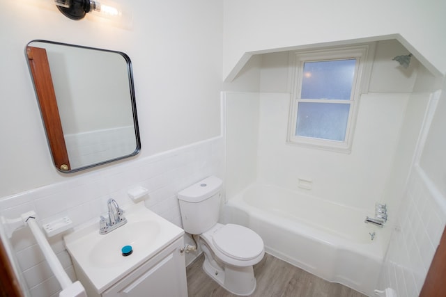 full bathroom with hardwood / wood-style floors, vanity, bathing tub / shower combination, toilet, and tile walls