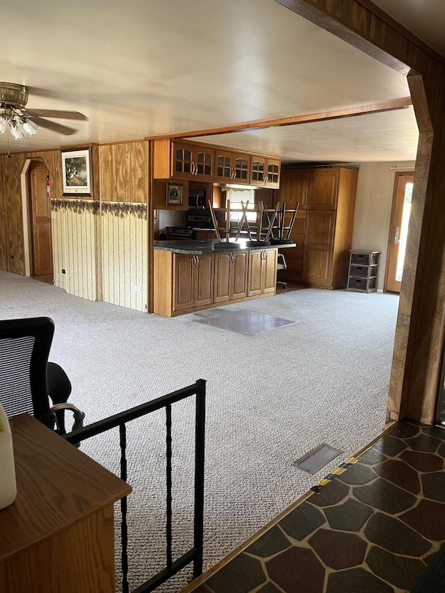 kitchen featuring carpet flooring, ceiling fan, and wood walls