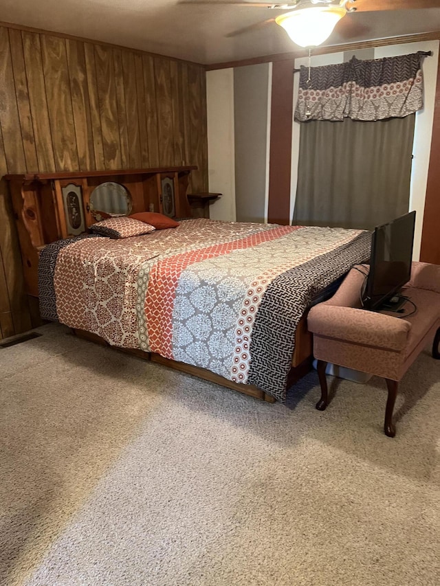 bedroom featuring ceiling fan, wooden walls, and carpet