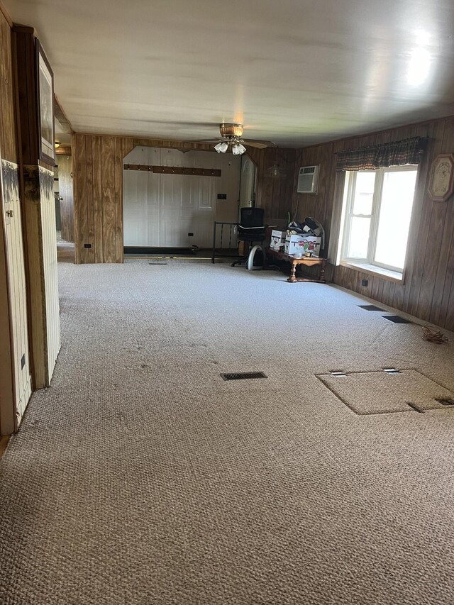 8181 15 Mile Rd, Evart, MI 49631 - living area featuring carpet, a ceiling fan, wood walls, an AC wall unit, and a wood stove