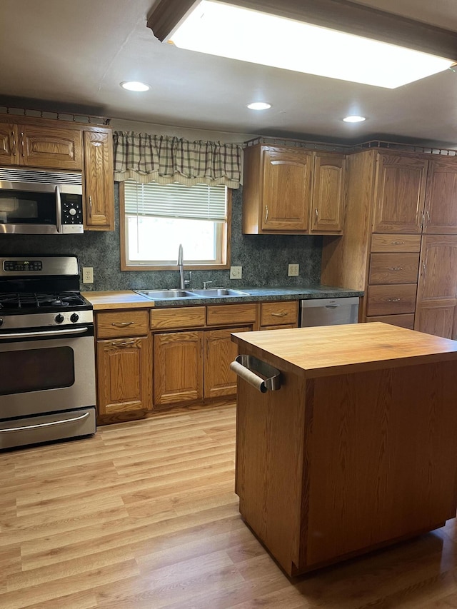 kitchen featuring butcher block counters, sink, backsplash, light hardwood / wood-style floors, and appliances with stainless steel finishes