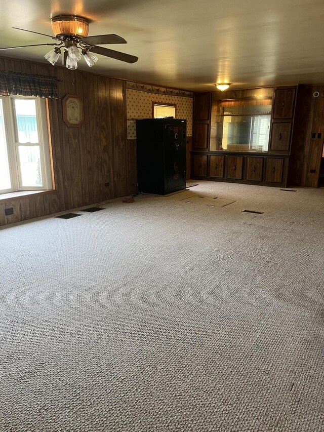 8181 15 Mile Rd, Evart, MI 49631 - unfurnished living room featuring a ceiling fan, carpet, and wooden walls