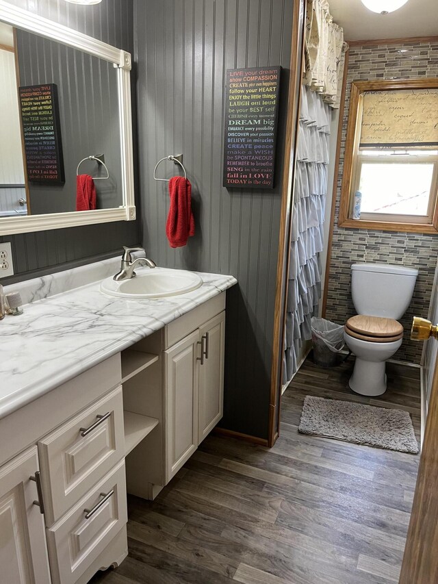 bathroom with brick wall, vanity, hardwood / wood-style flooring, toilet, and wood walls