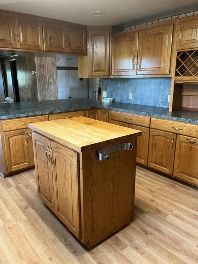 kitchen featuring backsplash, butcher block counters, a kitchen island, and light wood-type flooring