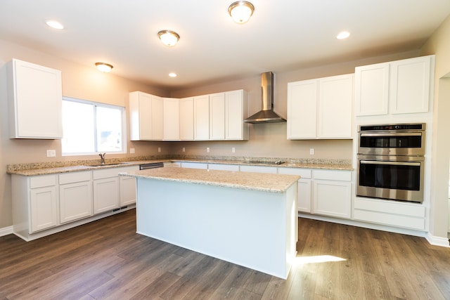 kitchen with cooktop, stainless steel double oven, white cabinetry, and wall chimney exhaust hood