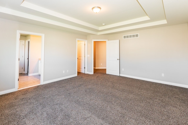 unfurnished bedroom with carpet floors, baseboards, visible vents, and a raised ceiling