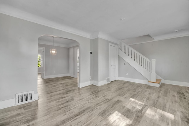 unfurnished living room with light hardwood / wood-style floors, an inviting chandelier, and ornamental molding