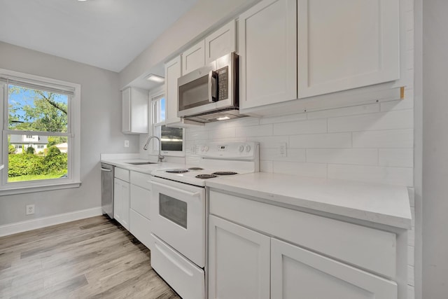 kitchen featuring sink, decorative backsplash, appliances with stainless steel finishes, light hardwood / wood-style floors, and white cabinetry