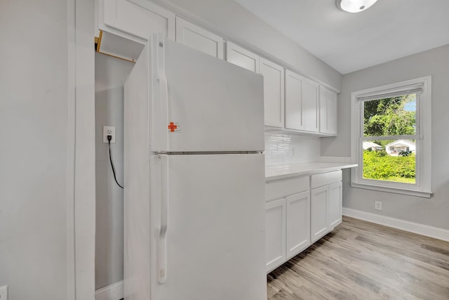 kitchen with decorative backsplash, white fridge, white cabinetry, and light hardwood / wood-style floors