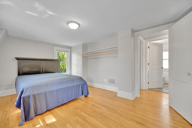 bedroom featuring connected bathroom and light hardwood / wood-style flooring