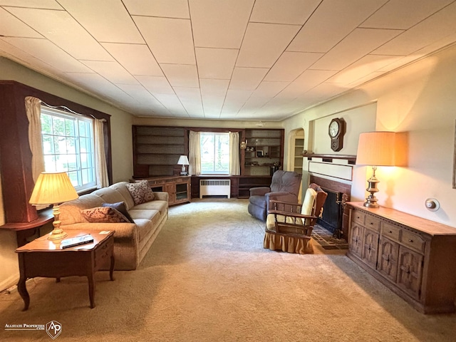 living area with carpet floors, radiator, a brick fireplace, and arched walkways