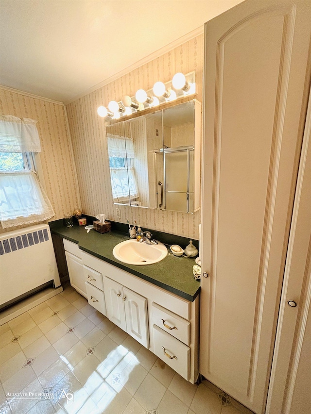 bathroom with vanity, radiator, wallpapered walls, a shower stall, and crown molding