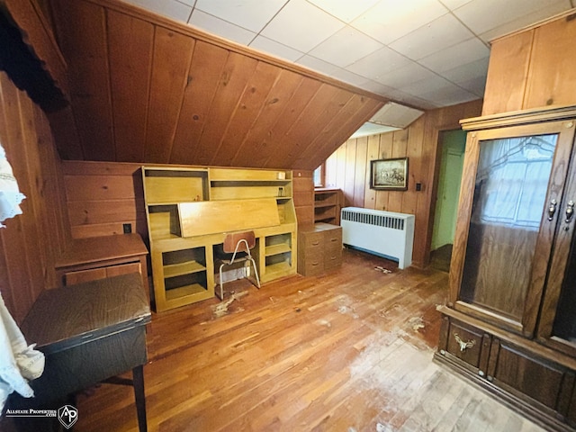 interior space with wooden walls, radiator, lofted ceiling, and wood-type flooring