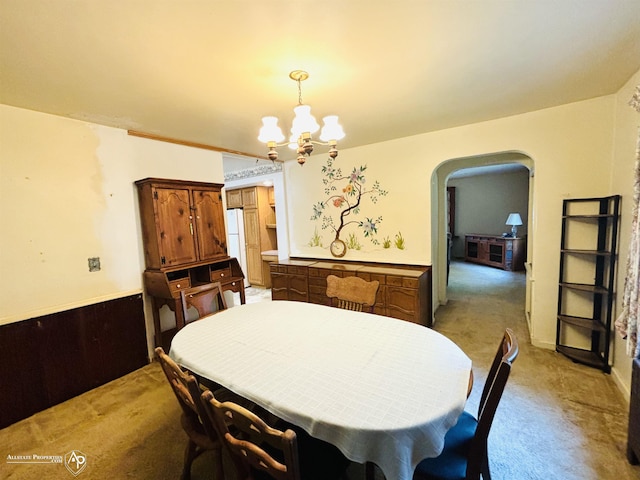 dining area with a notable chandelier, arched walkways, and light carpet