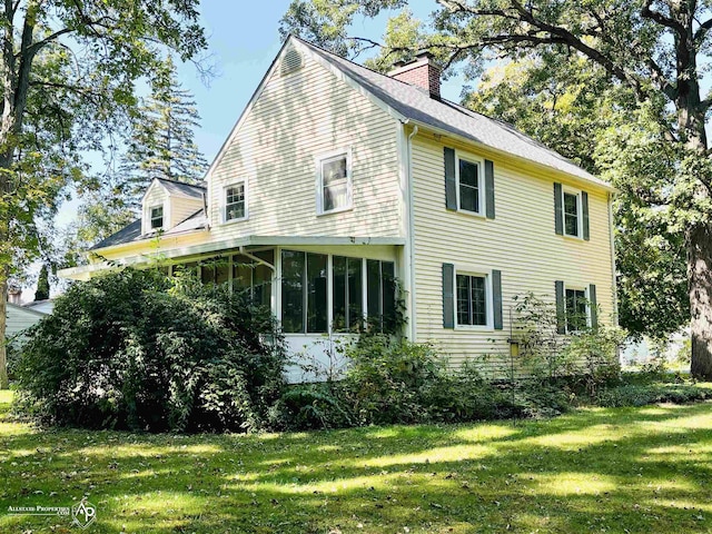 view of home's exterior with a sunroom and a yard