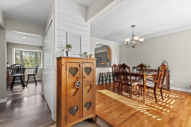 dining area featuring wood-type flooring, an inviting chandelier, and crown molding